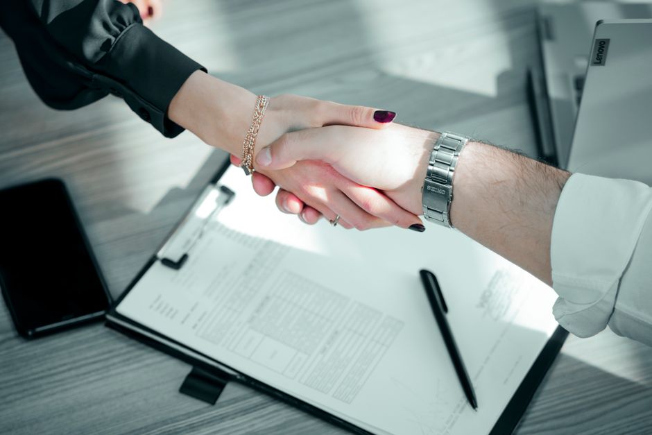 Close-up of a professional handshake over a contract, symbolizing a successful business deal.
